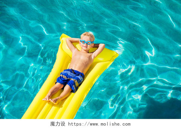 小男孩躺在泳池充气筏上放松